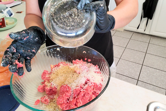 Woman mixing in rice and spices to a bowl of hamburger meat