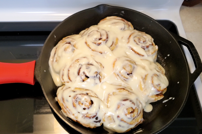 Cast Iron Skillet filled with frosted sourdough cinnamon rolls