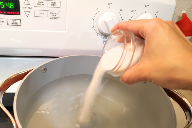 woman pouring salt into a large pot of water