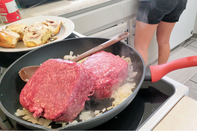 a skillet filled with 2 pounds of hamburger meat, onion, and garlic