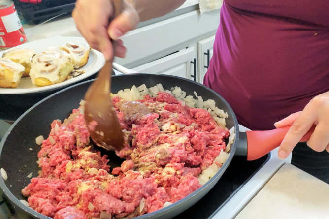 woman stirring spices in hamburger meat