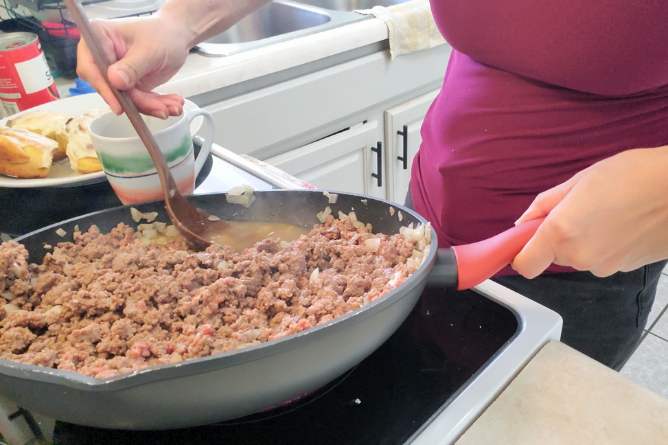 woman draining fat from hamburger meat with a large brown spoon